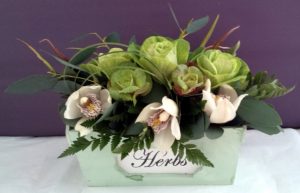 Vintage pink and green flowers arranged in a herb box