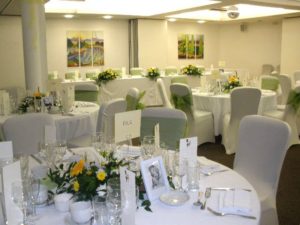 Yellow, white and green bespoke wedding flowers on reception tables by Shrinking Violet